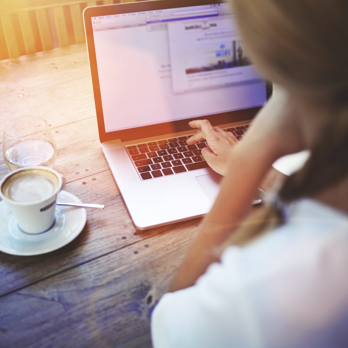 Personne utilisant un ordinateur portable avec une tasse de café